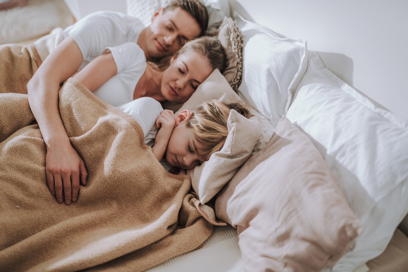 family sleeping peacefully in bed