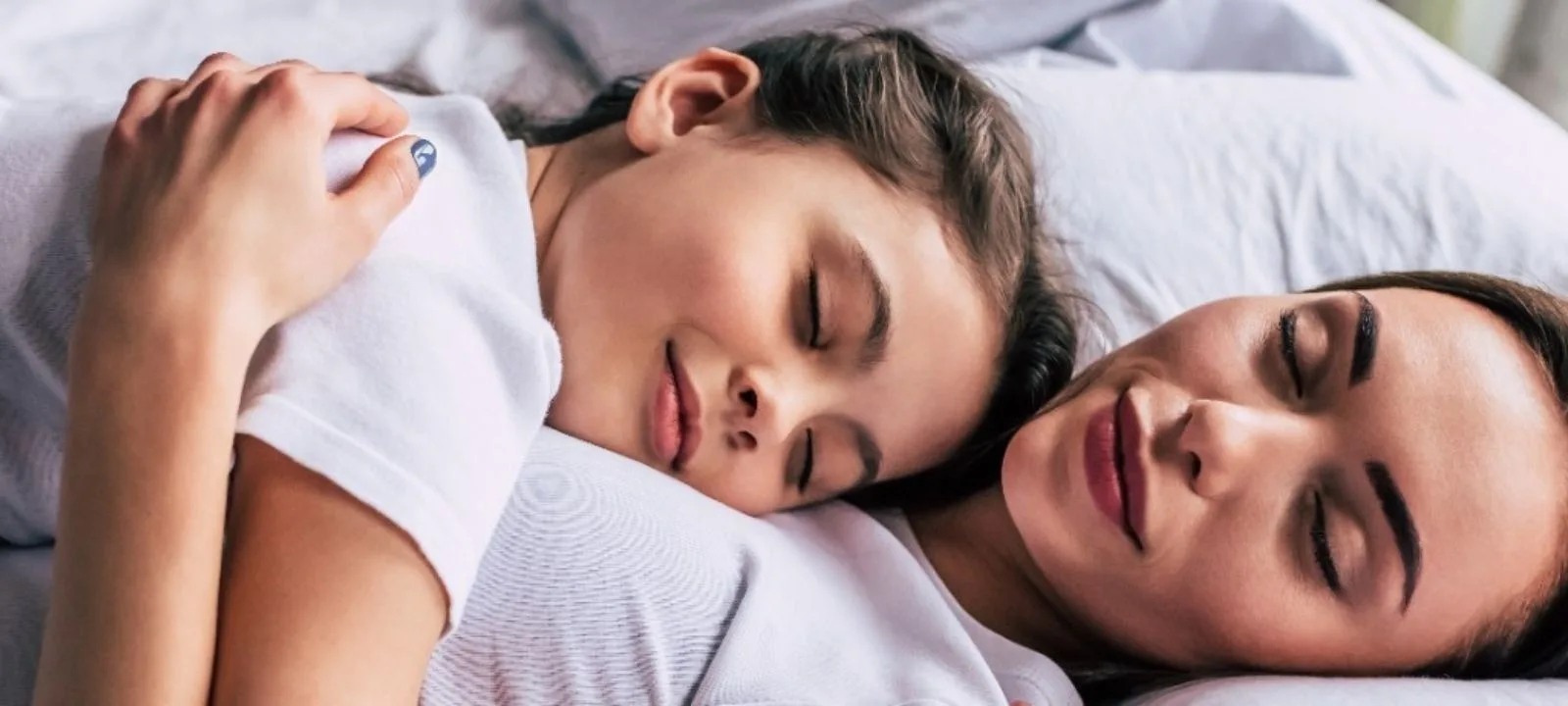 A person lying calmly on their side in bed in soft early-morning light, eyes closed and relaxed