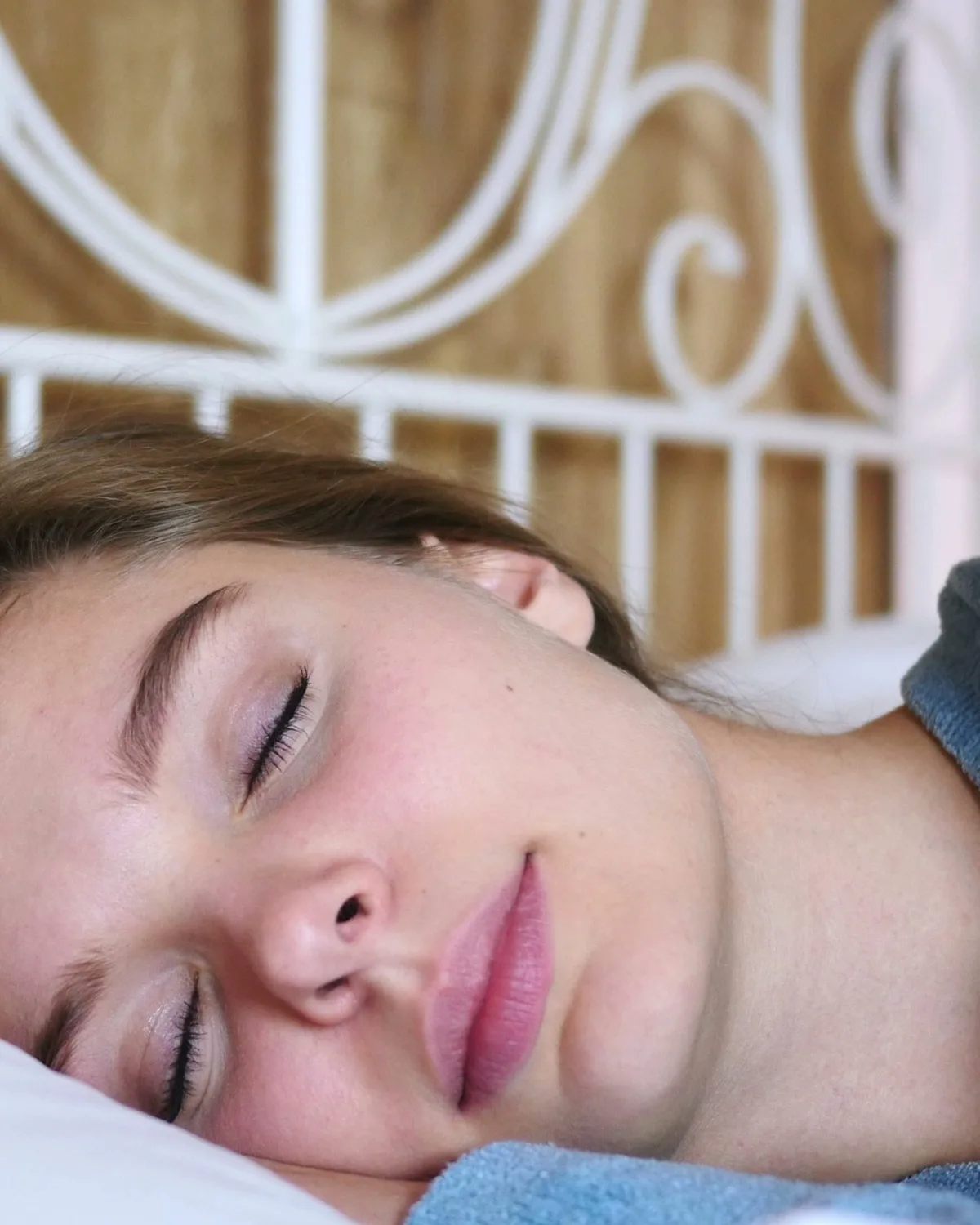 A young woman asleep in bed, resting on a white pillow