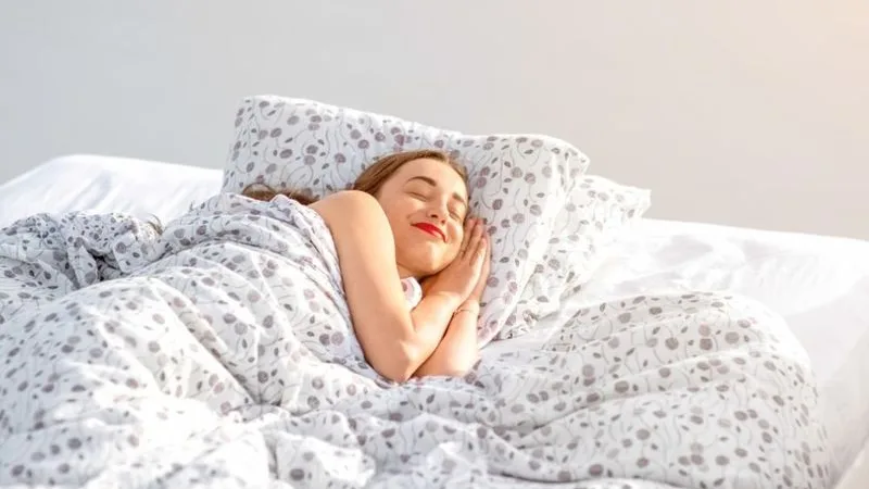 A woman waking in a sunlit bedroom