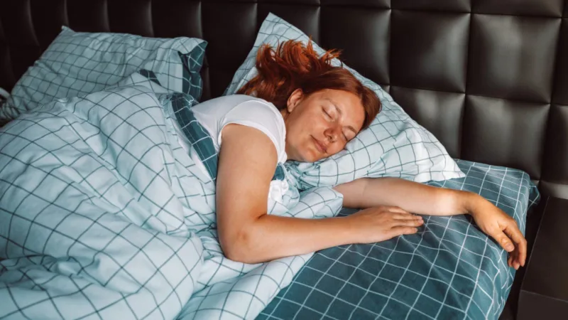 Woman sleeping peacefully under a checked duvet